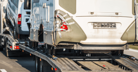 Camper met schade wordt vervoerd op een vrachtwagen naar een schadeherstelbedrijf